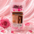 Saco de sal de banho Pomba Gira Atração Sexual sobre tecido rosa, com rosas e cristais de quartzo rosa