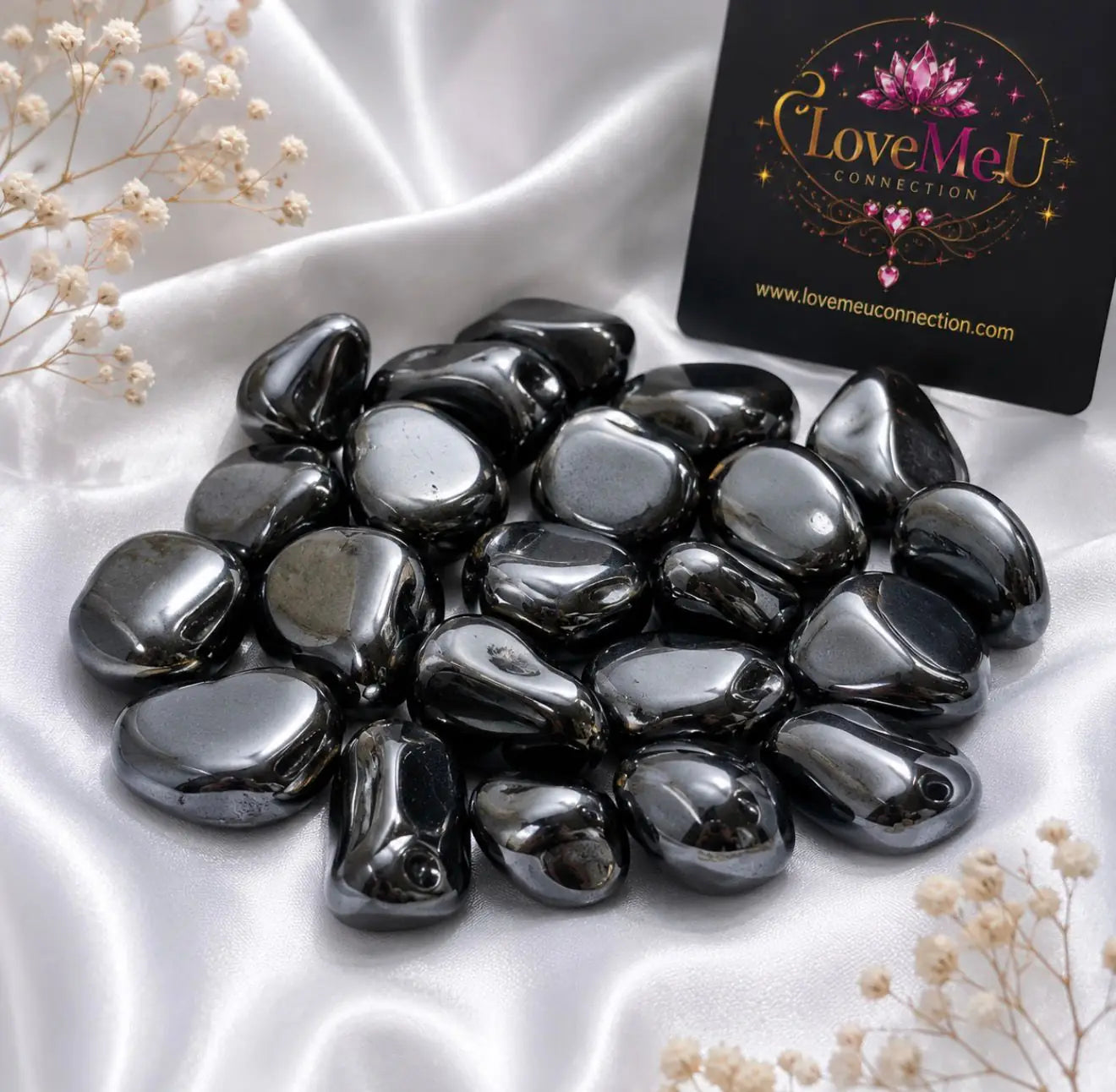 Pedras de hematite natural sobre tecido branco, com cartão LoveMeU Connection ao fundo