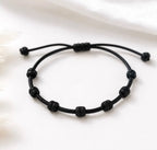 Pulseira ajustável de 7 nós em cordão preto, isolada em fundo branco