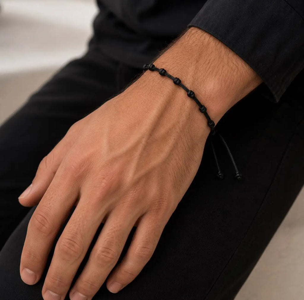Homem a usar a pulseira de 7 nós em cordão preto no pulso