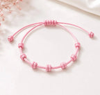 Pulseira ajustável de 7 nós em cordão rosa, isolada em fundo branco