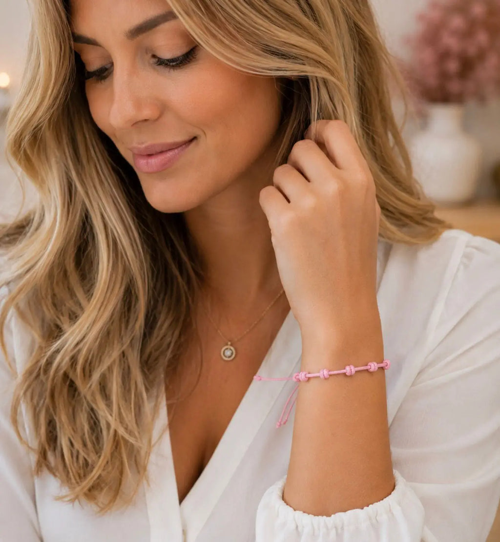 Mulher a usar a pulseira de 7 nós em cordão rosa no pulso, blusa branca