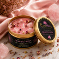 Vela Aromática Quartzo Rosa em lata dourada aberta, sobre tecido de cetim rosa com flores secas